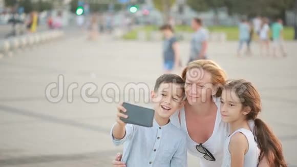 妈妈带着儿子和女儿正在做自拍手机上的家庭照片视频的预览图