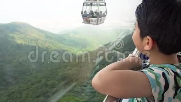 坐缆车的快乐亚洲男孩看着大自然山视频的预览图