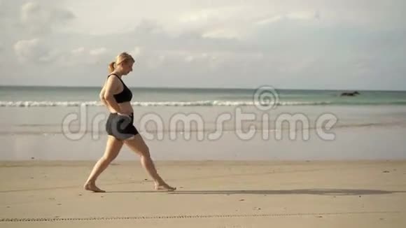 年轻的金发女人在海滩上做运动视频的预览图