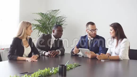 商务人士坐在一起举行非正式会议共同研究数字平板电脑的数据视频的预览图