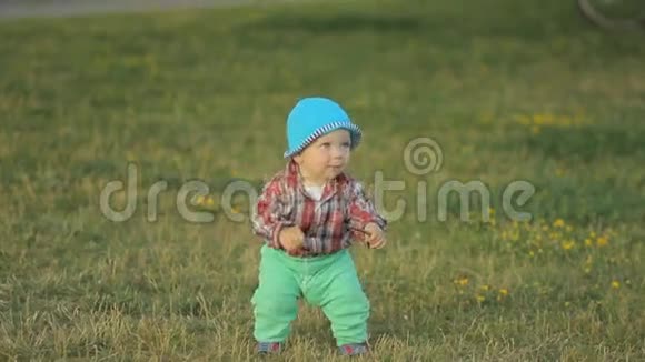 可爱的小男孩在草地上的公园里迈出第一步视频的预览图