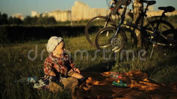 夏天日落时分戴着帽子的可爱小男孩坐在公园里一个孩子摘下帽子视频的预览图