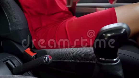 在驾驶前身着红色礼服的女士在车内系紧安全带视频的预览图
