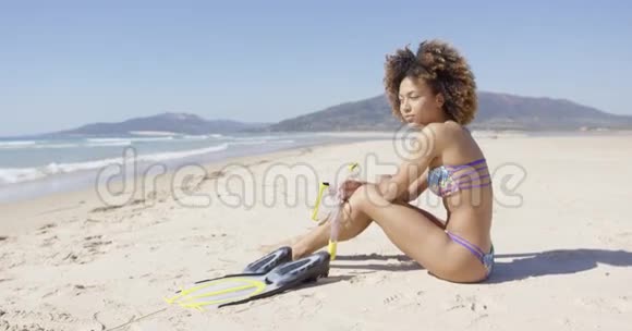 女人坐在沙滩上用脚蹼视频的预览图