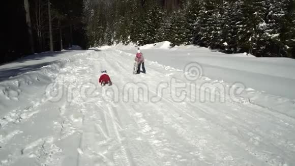 冬天两个快乐美丽的孩子在雪山上玩着有趣的雪橇兄弟和兄弟视频的预览图