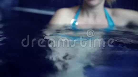 手和穿着蓝色比基尼的年轻女人在游泳池里视频的预览图
