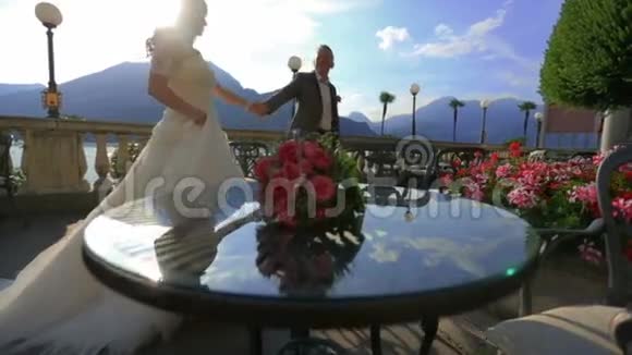 快乐的新娘和新郎在夏天的露台上散步和牵手意大利科莫湖视频的预览图