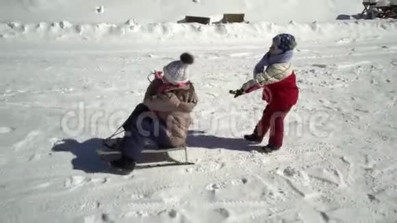 冬天两个快乐美丽的孩子在雪山上玩着有趣的雪橇兄弟和兄弟视频的预览图