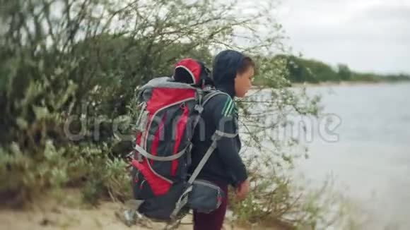 沙滩上背着旅游背包的小男孩视频的预览图