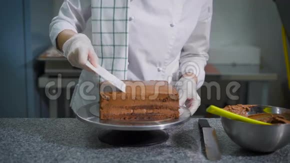 一个面包店的专业厨房里一个带抹刀的糖果把巧克力撒在刚出炉的蛋糕上厨师视频的预览图