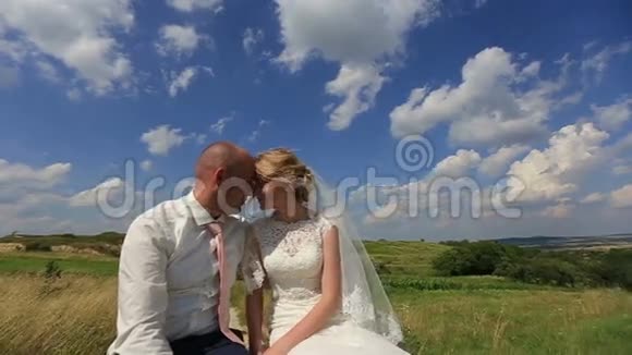 美丽的新婚新娘和新郎在绿色的春田里对抗蓝天爱的时刻视频的预览图