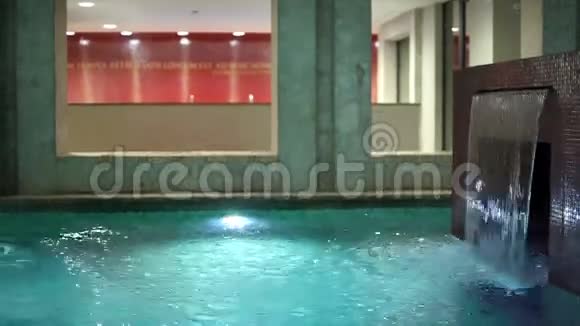 有瀑布和水下灯光的年轻夫妇在游泳池游泳视频的预览图