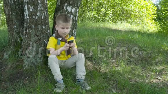 快乐的小男孩在公园里用智能手机视频的预览图