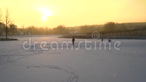 儿童在池塘湖上滑冰日落黄昏视频的预览图