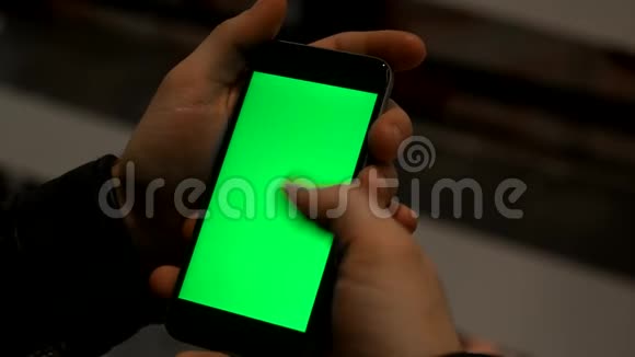 特写男性手拿智能手机与绿色屏幕预键效果视频的预览图