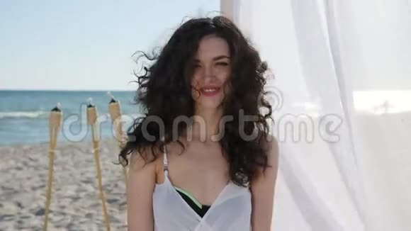 美丽的脸庞微笑的女性海滩上的平房白色的窗帘在海洋中度过暑假的女性快乐视频的预览图