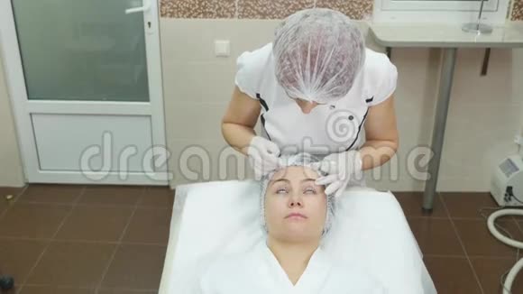 医生在病人脸上用记号笔画出线用于诊所的面部整形手术视频的预览图