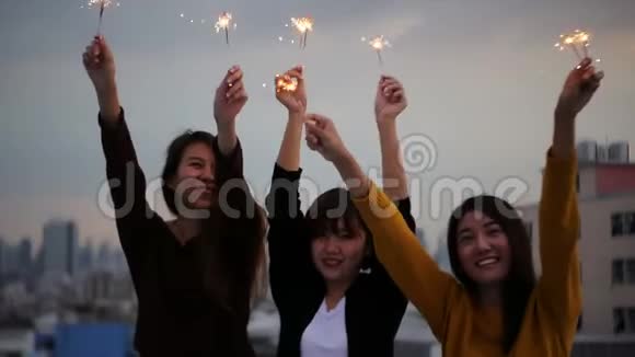 在屋顶派对上拍摄的年轻人的户外照片快乐的亚洲女孩朋友在屋顶聚会上享受和玩火花视频的预览图