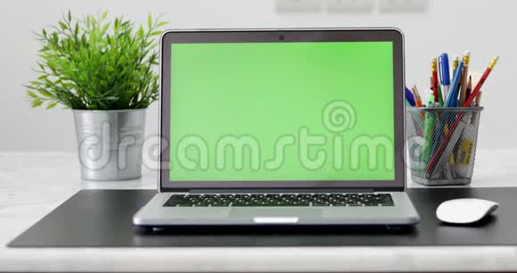 4K一台笔记本电脑在工作办公室桌子上设置一个绿色的关键屏幕多利在视频的预览图