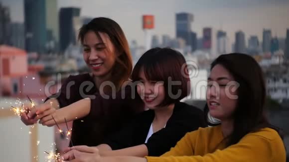 在屋顶派对上拍摄的年轻人的户外照片快乐的亚洲女孩朋友在屋顶聚会上享受和玩火花视频的预览图