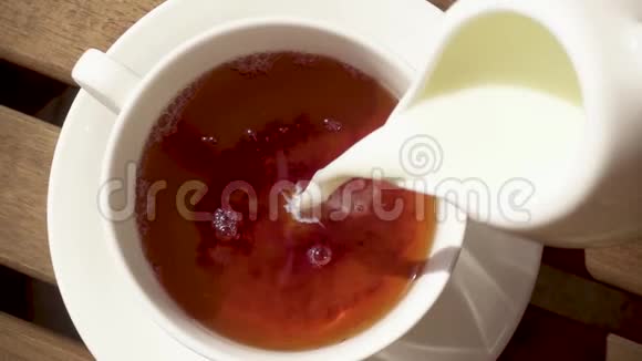 木桌上的茶托上的白瓷杯热饮慢动作视频的预览图