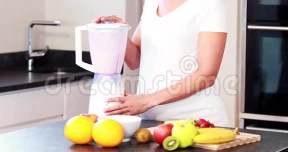 孕妇在厨房里混合一些水果视频的预览图