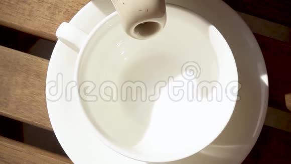 木桌上的茶托上的白瓷杯热饮慢动作视频的预览图