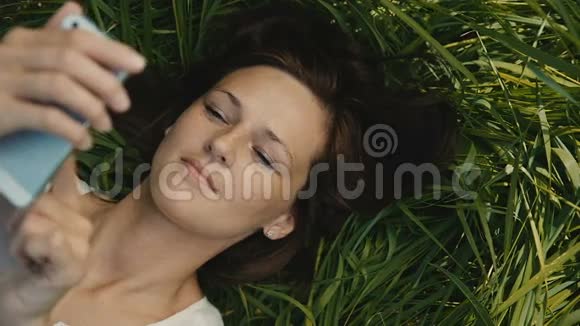 女人在草地上休息用你的智能手机视频的预览图