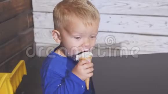 坐在高椅子上吃冰淇淋的男孩可爱的孩子在华夫饼锥里享受冰淇淋看着视频的预览图
