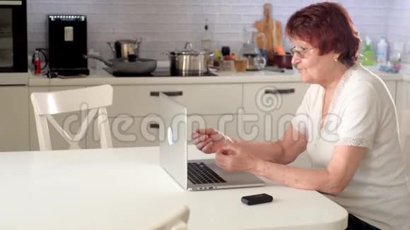 老妇人用笔记本电脑通过Skype与孙女交谈视频的预览图