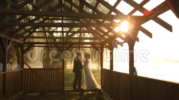 新婚快乐的一对新婚夫妇在结婚当天晚上的海边小屋门口亲吻视频的预览图