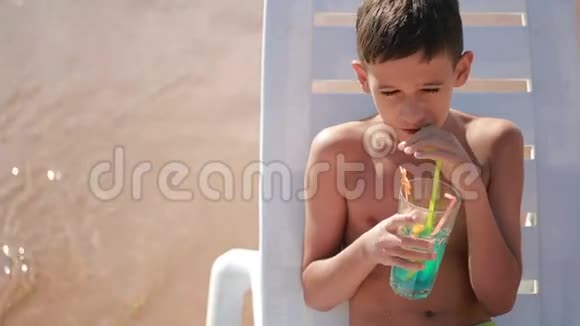 在热带海滩喝鸡尾酒的男孩视频的预览图