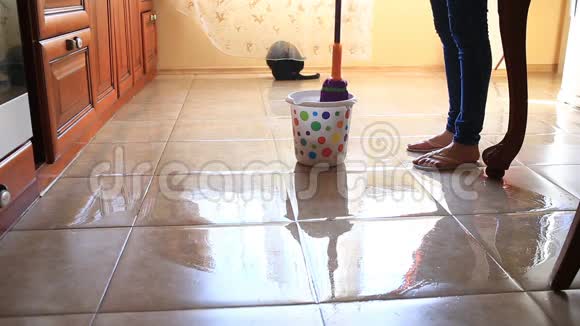一个女人用拖把洗厨房里的地板在五颜六色的桶里蘸一块抹布从上面看视频的预览图