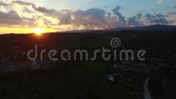 乘着美丽的日出飞越青山和村庄视频的预览图