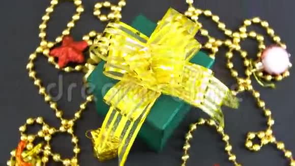 美丽的圣诞绿色礼品盒金色的蝴蝶结和装饰旋转在黑色的背景无缝可循环视频的预览图