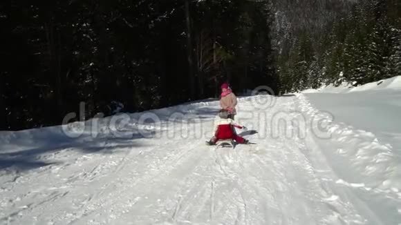 冬天两个快乐美丽的孩子在雪山上玩着有趣的雪橇兄弟和兄弟视频的预览图