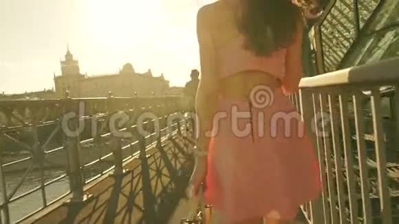美丽的黑发女孩穿着粉红色的裙子走在桥上慢动作安定夹视频的预览图