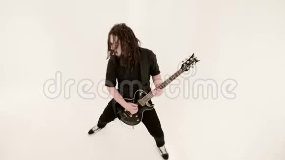 时尚的独奏吉他手头上戴着可怕的石头白色背景上穿着黑色衣服富有表现力地演奏着视频的预览图