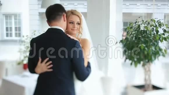 华丽的新娘和新郎在豪华餐厅举行婚礼时轻轻拥抱视频的预览图