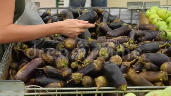 一个女人在蔬菜货架上的超市里买蔬菜和水果一个人从腐烂的地方选择茄子视频的预览图