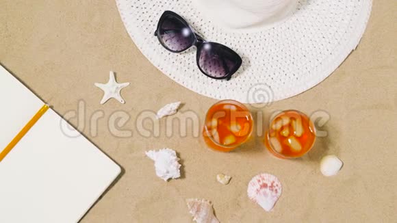 沙滩沙上的笔记本鸡尾酒帽子和墨镜视频的预览图