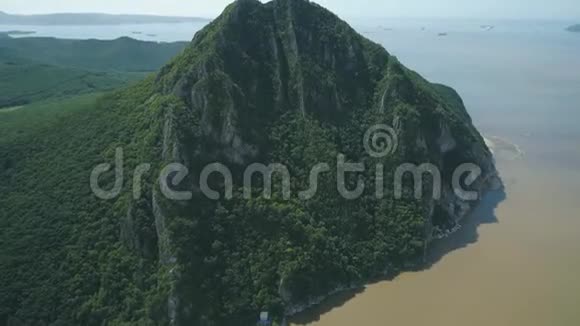 在阳光明媚的日子里高耸于空谷和大海之上的森林覆盖的高山的空中景色视频的预览图