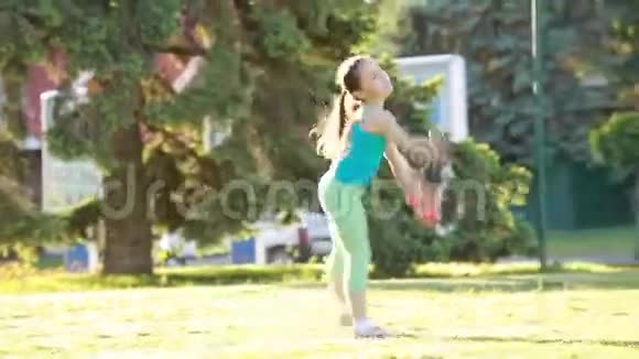 欢快快乐的小女孩在公园的绿草上跳舞玩耍视频的预览图
