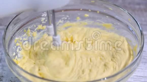 用搅拌器将白色奶油混合在碗中电动搅拌器搅拌碗中的奶油准备甜食做什么视频的预览图
