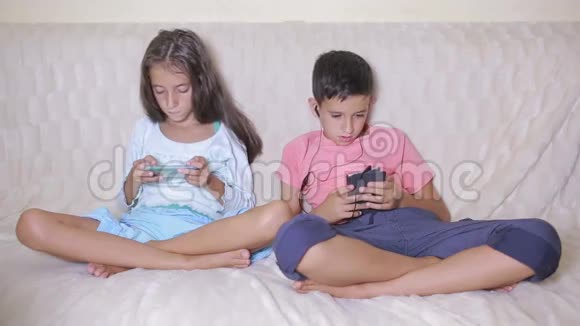 男孩和女孩拿着你的手机坐在沙发上网上游戏视频的预览图