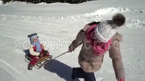 冬天两个快乐美丽的孩子在雪山上玩着有趣的雪橇兄弟和兄弟视频的预览图