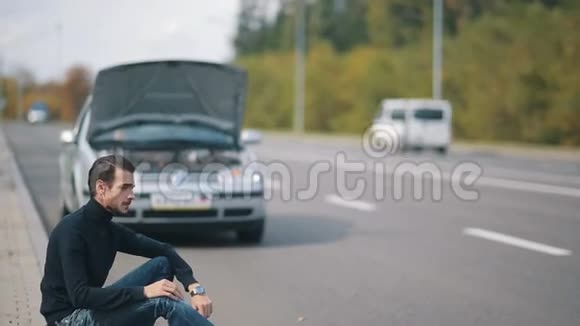 一个人坐在路上的破车前视频的预览图