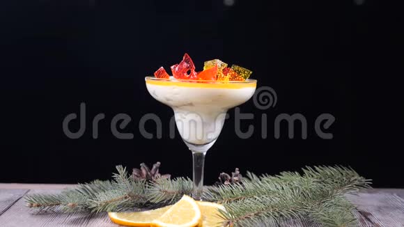 装饰着杉树枝和柠檬片的木板上的玻璃碗里的美味甜点孤立于黑色视频的预览图
