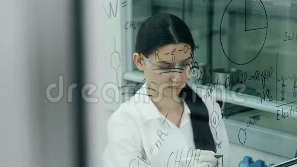 实验室里的女人在玻璃板上写配方视频的预览图