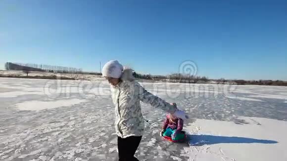 女孩在冰冻的湖面上雪橇姐姐视频的预览图